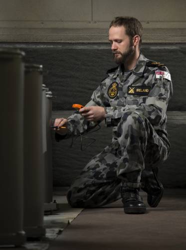 Petty Officer Bosun Luke Ireland conducts paint thickest checks on recently painted chaff launcher tubes at the HMAS Stirling Fleet Support Unit's Corrosion Control section.